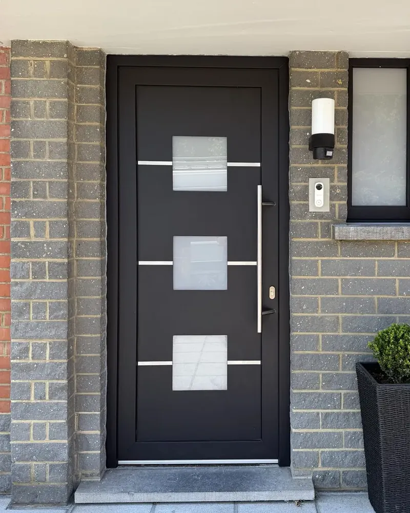 Porte d'entrée noire à carrés vitrés posée par MP Châssis